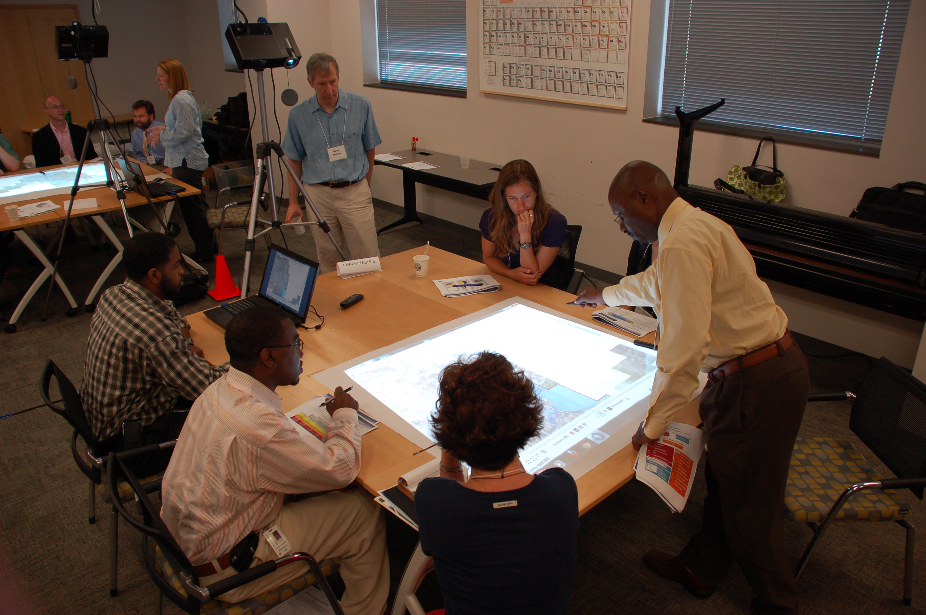 Participants gather around a projected map on a table.