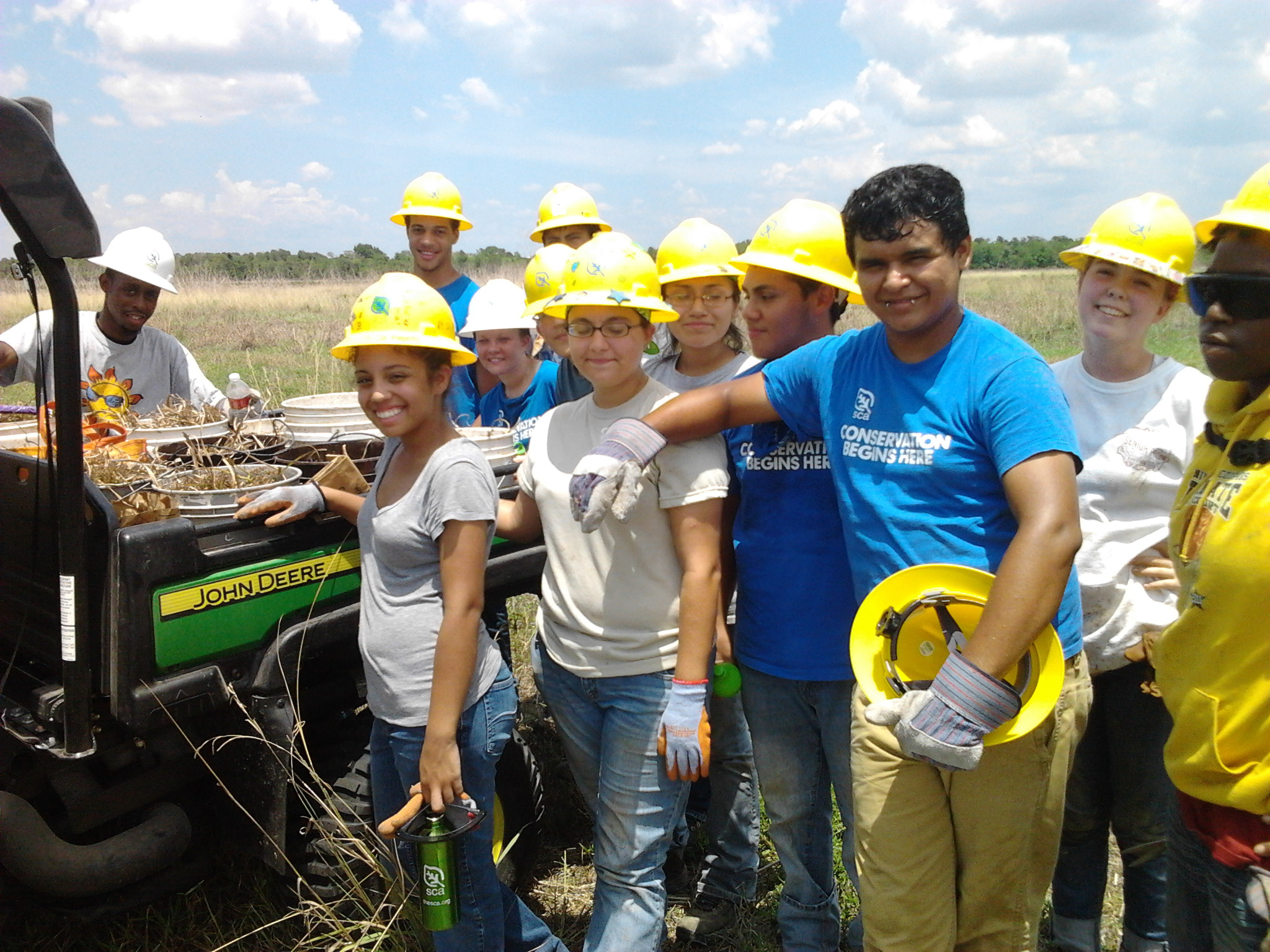 A group of SCA working posing around a UTV filled with buckets of prairie plants